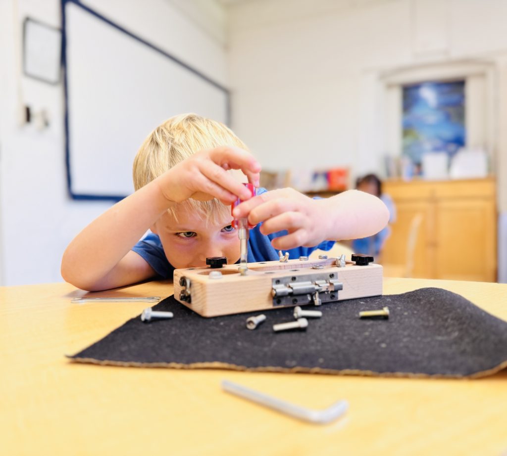 little blond boy working to build a machine