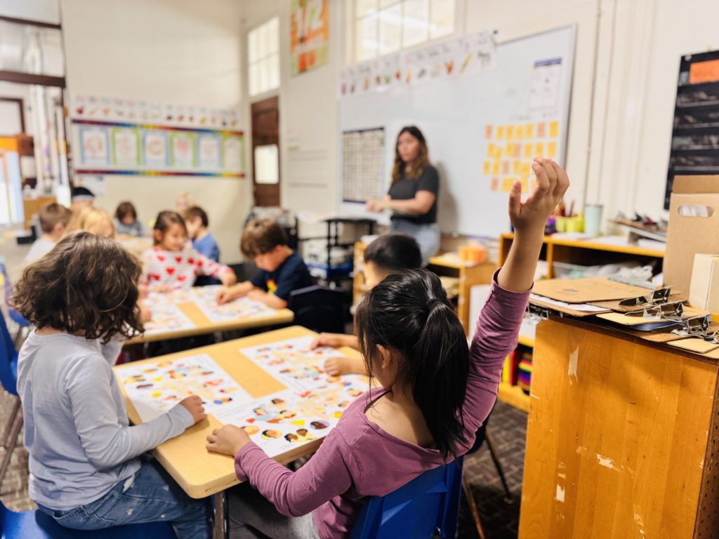 kids raising their hands in class
