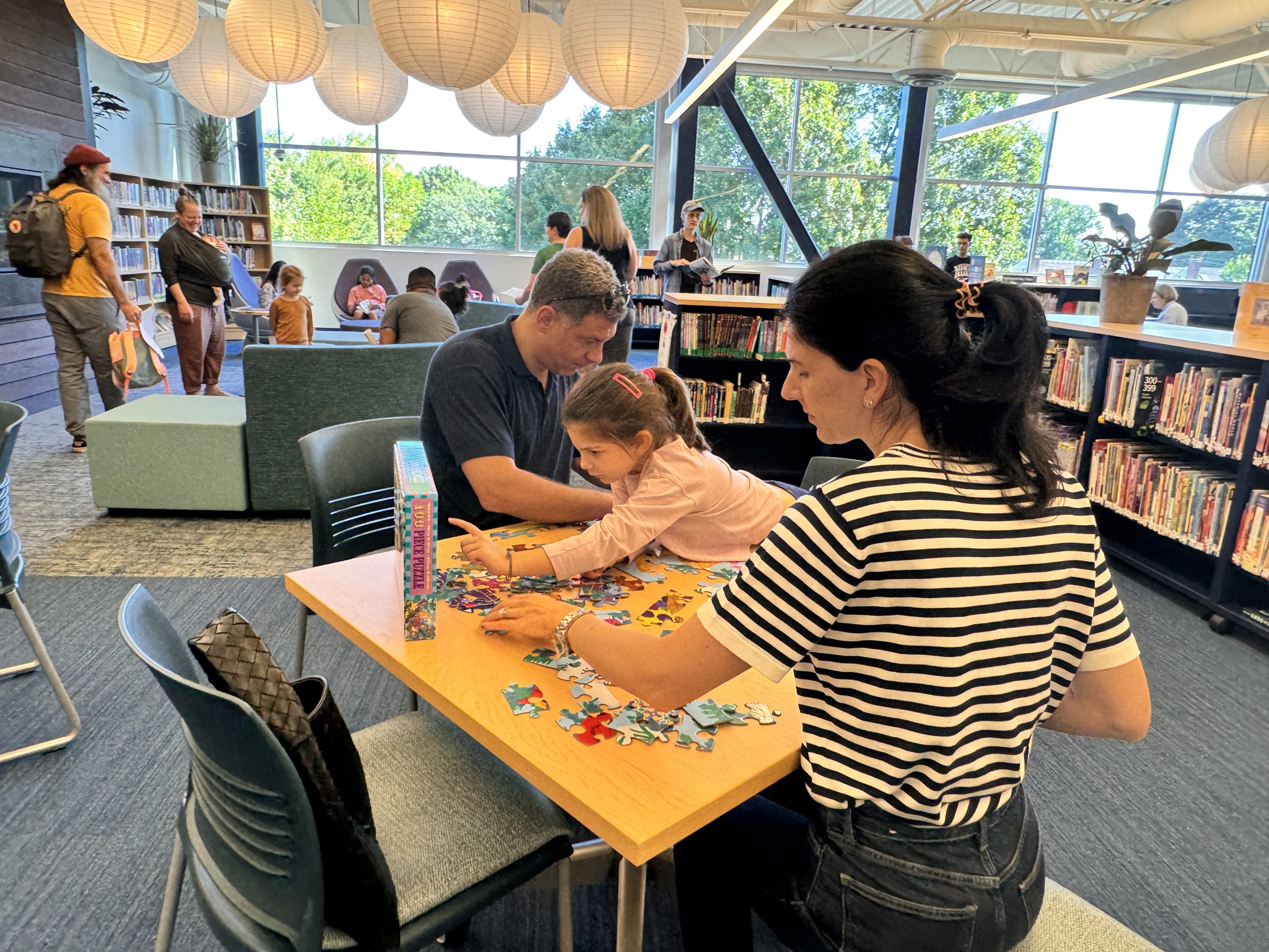parents help their daughter with a puzzle