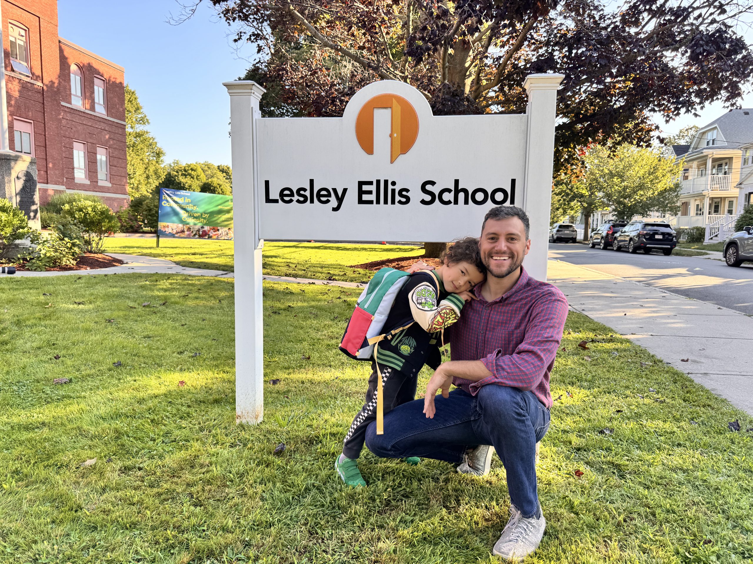 parent posing with their kid on first day of school